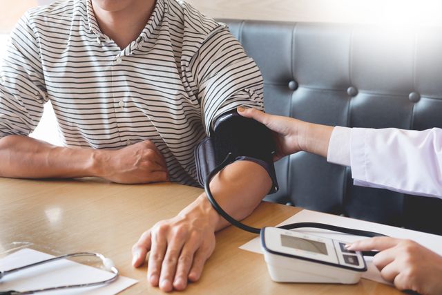 cropped image of doctor checking blood pressure of patient