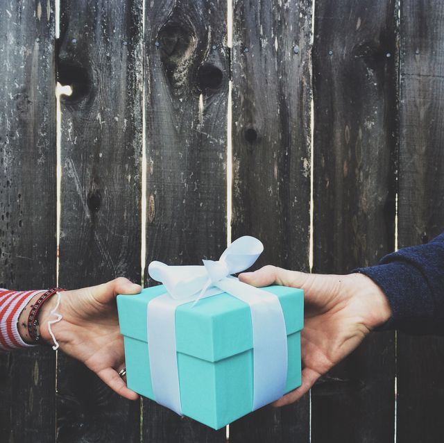 Cropped Image Of Hands Holding Gift Box Against Wooden Fence
