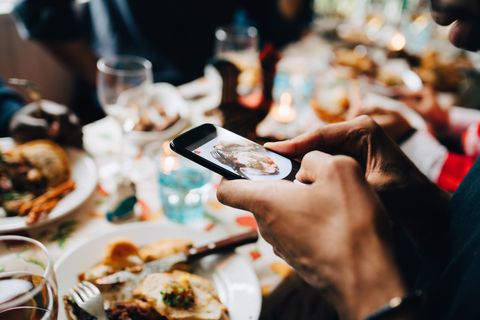 Cropped image of young man photographing food in plate at restaurant