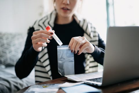 cropped shot of young asian woman consulting to her family doctor online in a virtual appointment, holding a medical test tube, conducting covid 19 diagnostic test at home