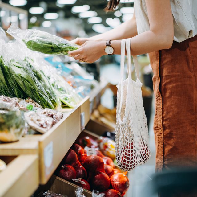 cropped shot of young asian woman shopping for fresh organic groceries in supermarket she is shopping with a cotton mesh eco bag and carries a variety of fruits and vegetables zero waste concept