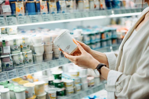 cropped shot of young asian woman shopping in the dairy section of a supermarket she is reading the nutrition label on a container of fresh organic healthy natural yoghurt