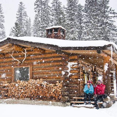 cross country skiers at a log cabin in falling snow