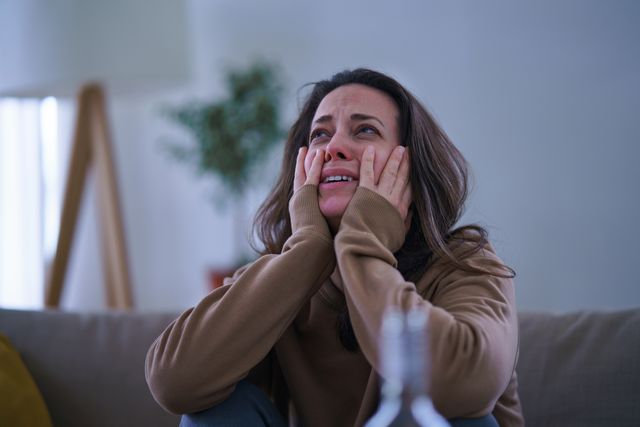 crying sad and depressed woman sitting indoors on sofa