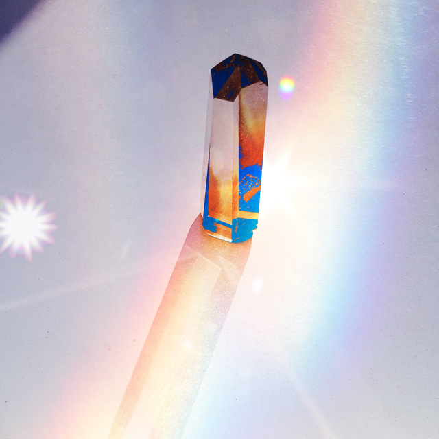 a rainbow light shines through a quartz crystal point