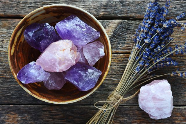 a table top image of a pottery bowl with large rose quartz and amethyst crystal with dried lavender flowers