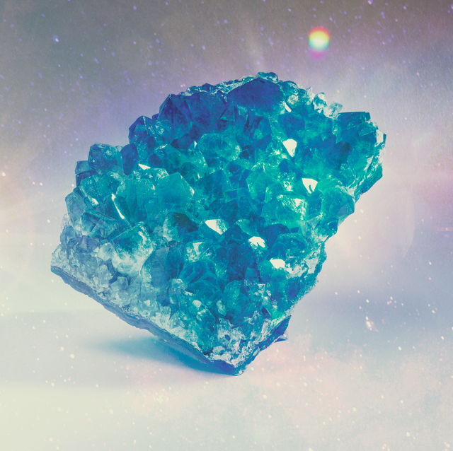 a blue crystal sits on a rainbow background