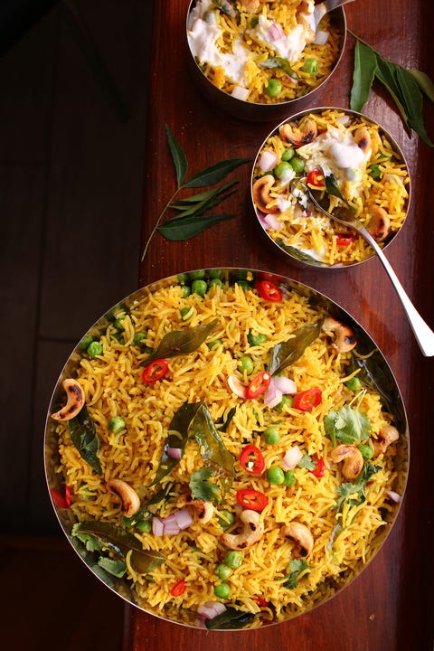 bowl of yellow curry rice topped with vegetables and toasted cashews