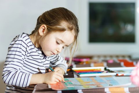 cute little girl painting by colorful pencil at home