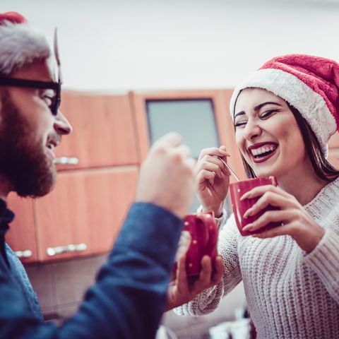 cute smiling couple drinking hot drink at christmas party