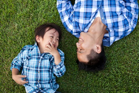 father and son laughing in grass