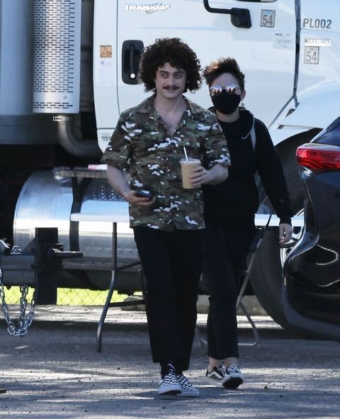 daniel radcliffe with a curly bob and mustache filming for al yankovic movie