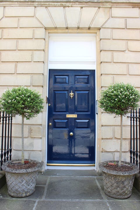 Dark blue front door on Georgian house, standard bay trees