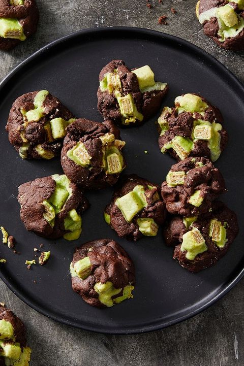 dark chocolate and green candy cookies on a black plate