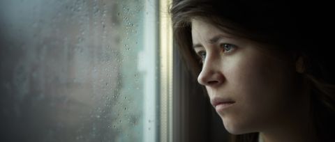 een vrouw kijkt angstig uit het raam