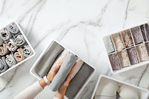 woman hands neatly folding underwears and sorting in drawer organizers on white marble background closet tidying and decluttering concept copyspace hypoallergenic fabric organic cotton