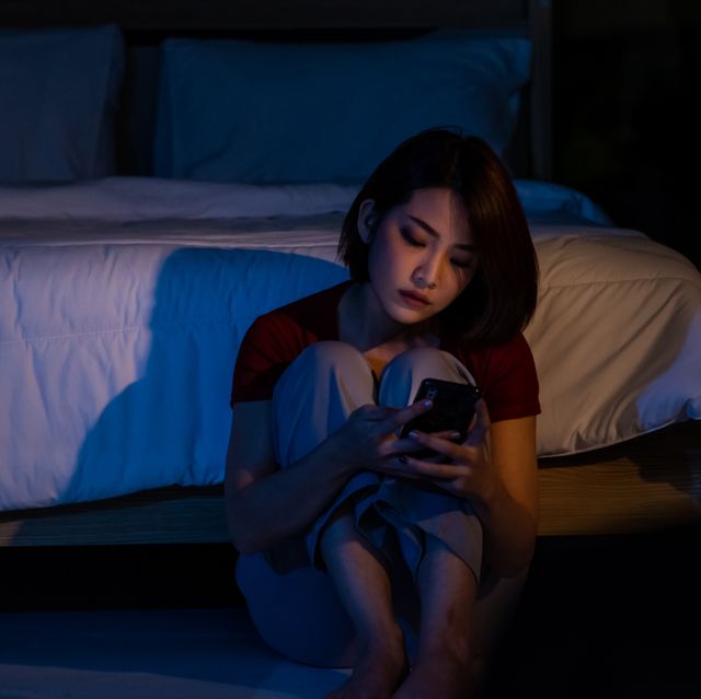 depressed young beautiful asian woman sitting alone on bedroom floor with looking at smartphone stressed insomnia sad woman having life problems mental health, healthcare and social issue concept