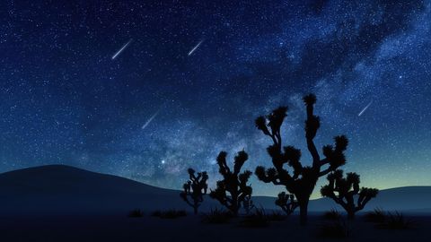desert landscape with falling stars in night sky
