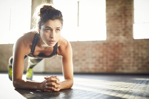 Determined young woman performing plank position in gym