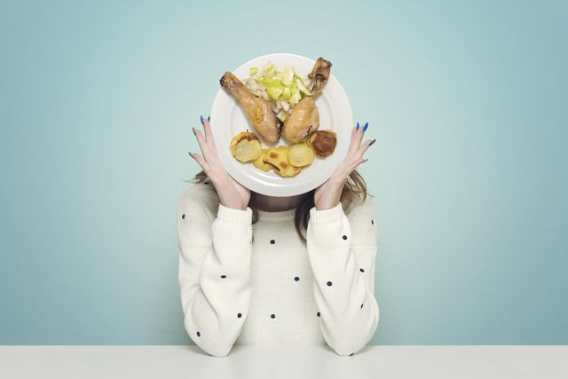 una donna solleva un piatto con carne bianca di pollo