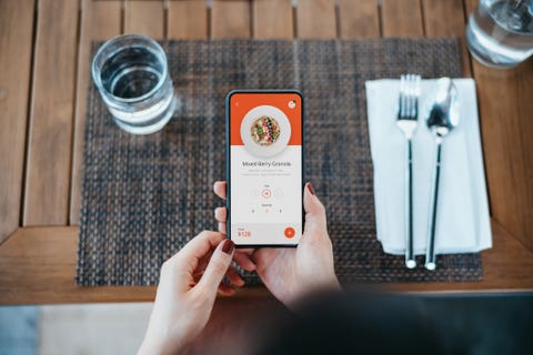 Overhead view of young Asian woman placing a food order and making contactless mobile payment with mobile app on smartphone in a restaurant. Eating out lifestyle. Contactless menu ordering and payment concept dieta mediterránea, la mejor para la salud y para adelgazar