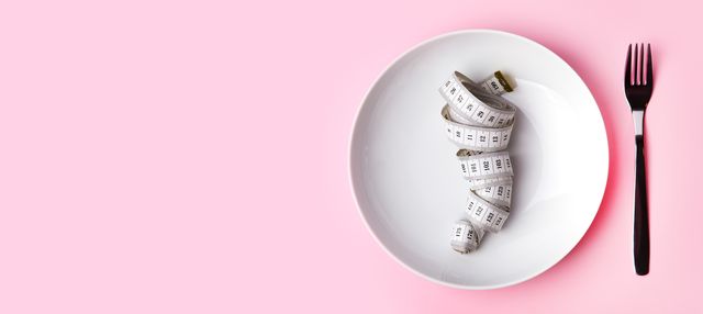 dieting and health care concept plate and cutlery with measuring tape