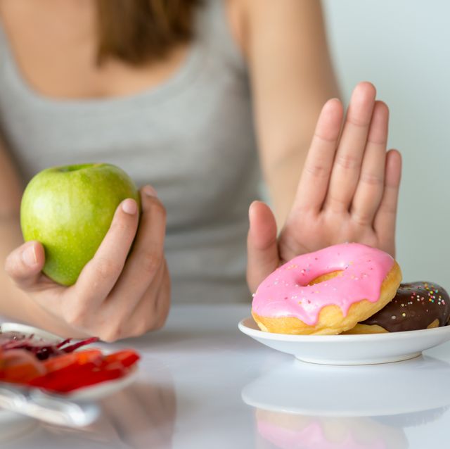 dieting or good health concept young woman rejecting junk food or unhealthy food such as donut or dessert and choosing healthy food such as fresh fruit or vegetable