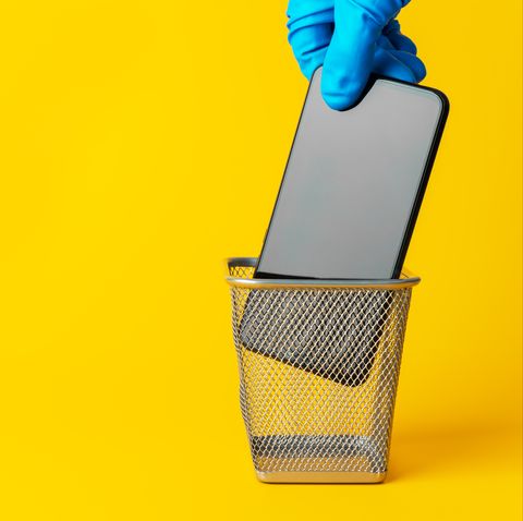 digital detox concept, a break from social media, smartphone in a trash can on a yellow background