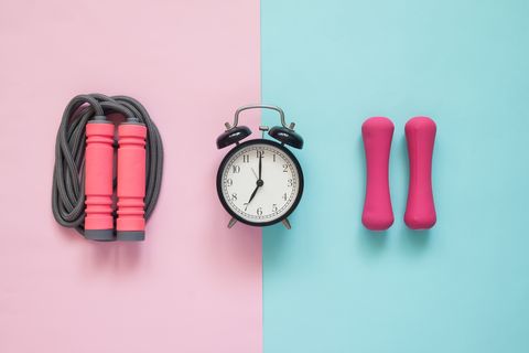Directly Above Shot Of Alarm Clock With Jump Rope And Dumbbells On Colored Background