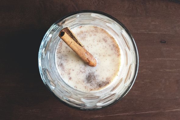 directly above shot of coquito with cinnamon in glass on wooden table