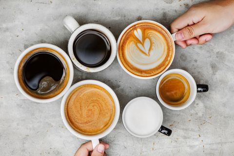 directly above shot of hands holding coffee cups on table
