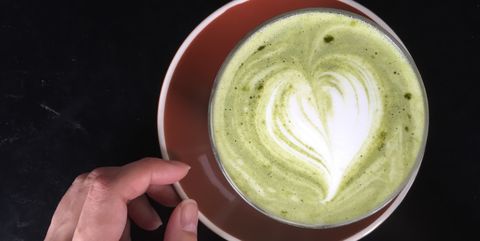 directly above shot of matcha latte in cup with cropped woman hand