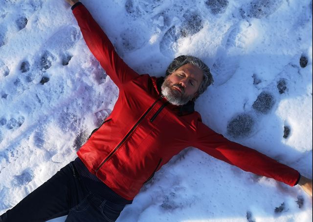 directly above shot of mature man lying on snow covered field