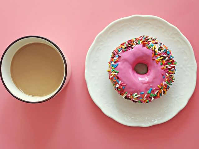Directly Above Shot Of Multi Colored Donut And Coffee On Pink Background