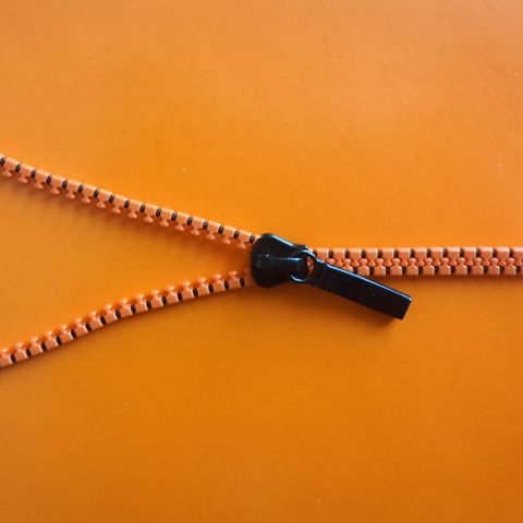 Directly Above Shot Of Zipper On Orange Background
