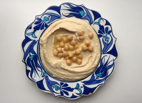 directly above view of fresh hummus with chick peas served in plate on white background