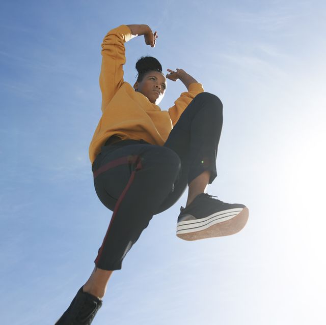 directly below shot of carefree woman jumping against blue sky