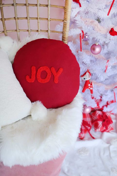 round red throw "joy" pillow on a wicker chair