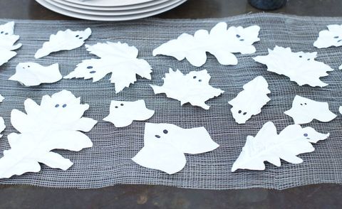 leaves painted white with two black eyes to look like ghosts displayed on table as diy halloween decorations