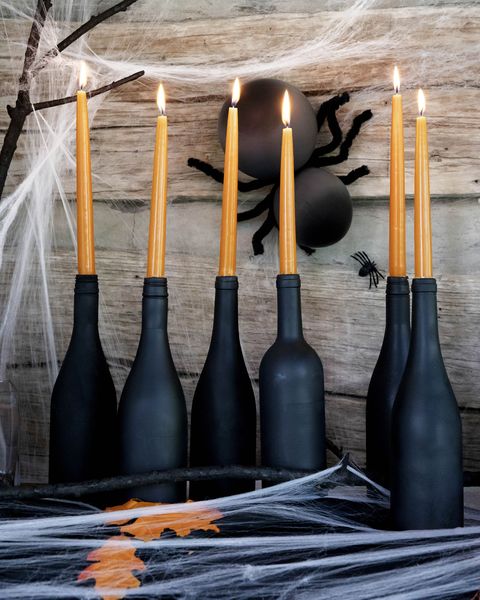 diy candlestick halloween decorations made from wine bottles painted black and filled with orange taper candles