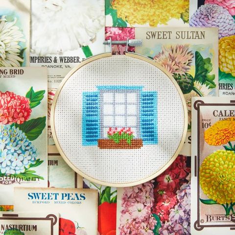 window box cross stitch for a diy mothers day gift, displayed in a wooden hoop on a background of seed packets