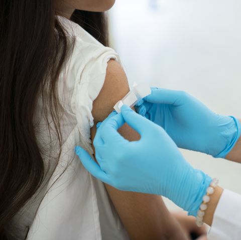 doctor applies bandage to preteen girl's arm following an immunization