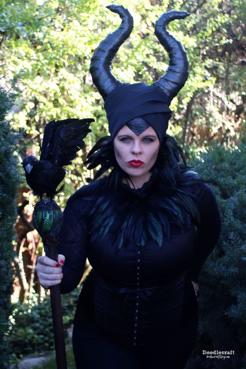 woman dresses as maleficent with staff topped by raven, horns and black feather collar