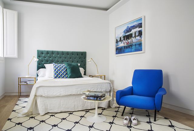 dormitorio con cabecero en capitoné verde y butaca en azulón