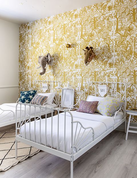 habitación infantil empapelada con el modelo jungle, pintado a mano, de these walls las camas son de ikea y los cojines llevan tejidos de designers guild