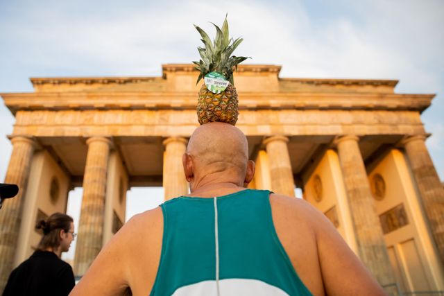 man loopt de hele marathon van berlijn met een ananas op zijn hoofd