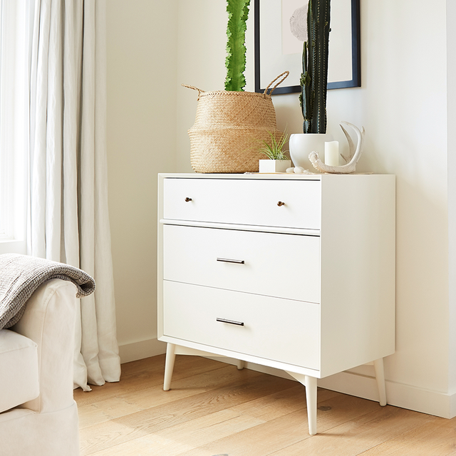 white dresser with cacti on top of it in bright bedroom