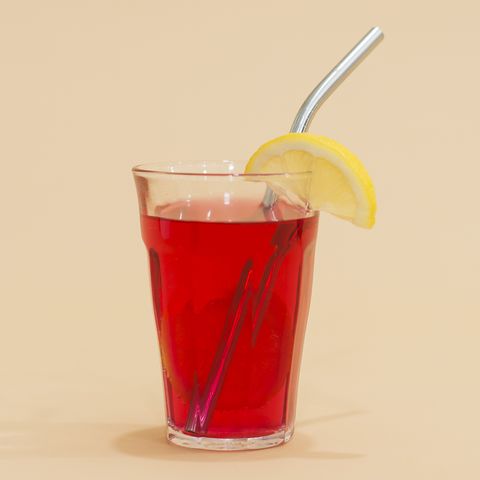 glass with reusable stainless steel straw and lemon in red drink