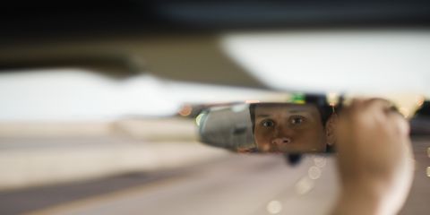 conductor conduciendo ajustando el espejo retrovisor