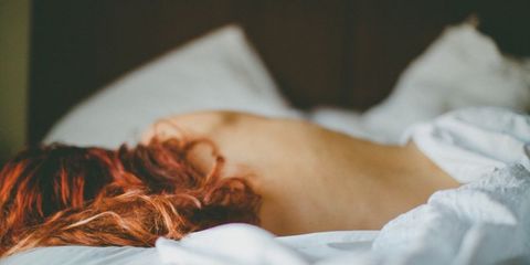 Vrouw met rood haar ligt in bed
